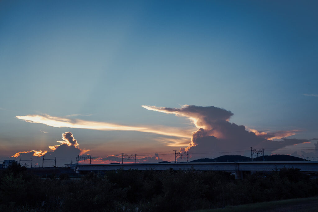 SONY α7C II / SIGMA 45mm F2.8 DG DNで撮影した夕暮れに染まる夏の雲と河川敷